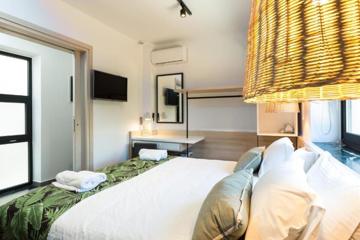 A hotel room with a bed, a bedside table, a TV, a mirror, and a window.