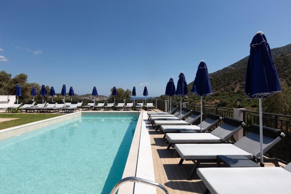 A poolside area with lounge chairs and umbrellas, overlooking a mountainous landscape.