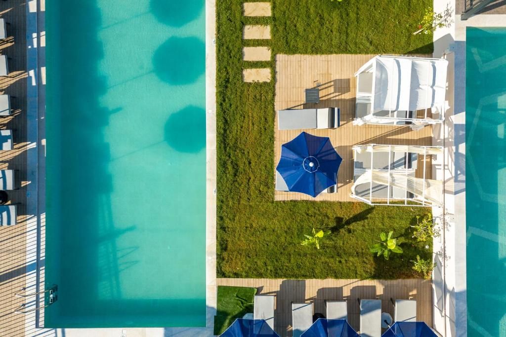An aerial view of a pool area with a clear blue pool, lounge chairs, umbrellas, and a wooden deck.