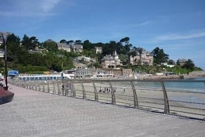 Eine Uferpromenade mit befestigtem Gehweg, Geländer und Gebäuden im Hintergrund.