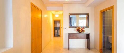 A hallway with a wooden door, a console table with a vase, and a mirror on the wall.