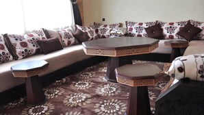 Una sala de estar con un sofá, dos mesas redondas y una alfombra estampada.