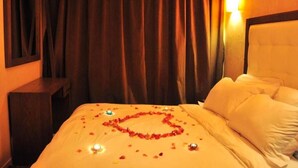 Una habitación de hotel con cama, mesita de noche, lámpara de pared y cortina.