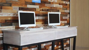 Zwei Monitore stehen auf einem hellen Schreibtisch vor einer Wand mit Holzpaneelen.