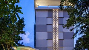 Ein Hotel mit modernem Design, das durch eine markante vertikale Lichtwand an der Fassade, einen überdachten Eingangsbereich und ein Schild mit dem Namen des Hotels gekennzeichnet ist.