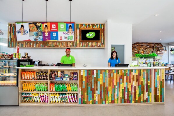 Um snack bar moderno com parede de madeira colorida, uma tela de TV e uma variedade de petiscos à mostra.