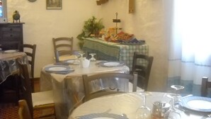 A dining area with round tables set for four, each with plates, cutlery, and glasses. There are chairs around the tables, and a small plant is visible on the tablecloth. - Bed and Breakfast Dessole (Olbia)