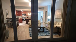 A modern living room with a sofa, coffee table, and a view of the kitchen through glass doors. - Lake Front-Private Beach Access- Golf - all within walking distance (Panama City)