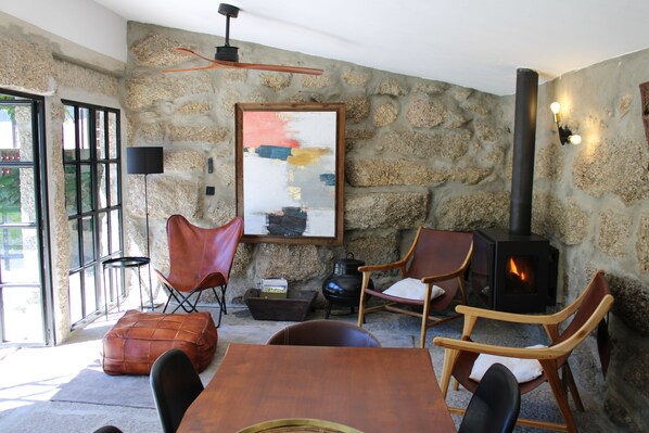 A stone-walled room with a fireplace, leather chairs, a wooden table, and a painting.