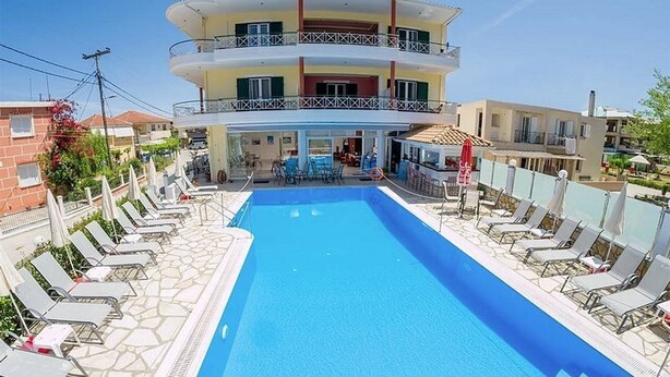 A hotel with a swimming pool surrounded by lounge chairs and a multi-story building with balconies. - Cosmopol Lefkada (Lefkada)