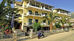 A multi-story hotel with balconies, palm trees, and a clear sky. - Cosmopol Lefkada (Lefkada)