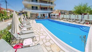 A hotel with a swimming pool, lounge chairs, and a two-story building with balconies. - Cosmopol Lefkada (Lefkada)
