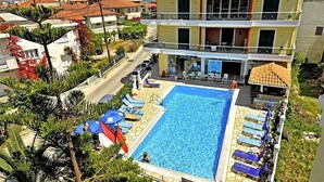 A two-story hotel with a swimming pool, outdoor seating, and a view of the surrounding neighborhood. - Cosmopol Lefkada (Lefkada)