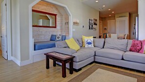 A living room with a built-in bench, a grey sectional sofa, and a wooden coffee table. - Cinnamon Shore- Porter Ansas TC 3302 (Port Aransas)