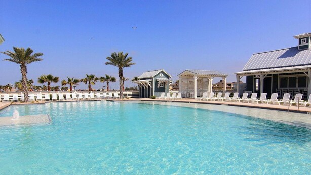 Une piscine d’un bleu éclatant, avec des chaises longues et des palmiers.