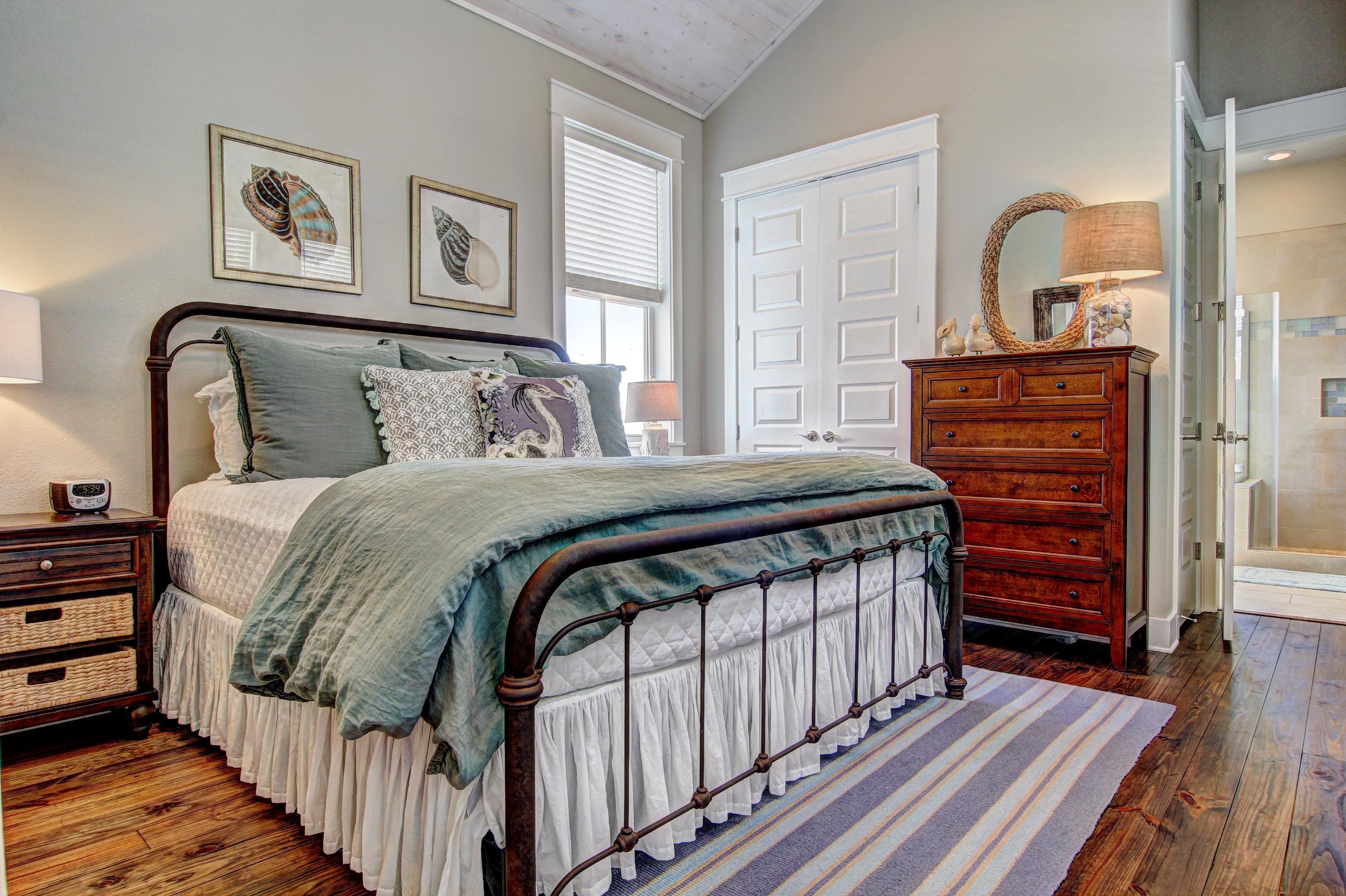 Une chambre à coucher comprenant un lit, une commode et une porte donnant sur une salle de bain.