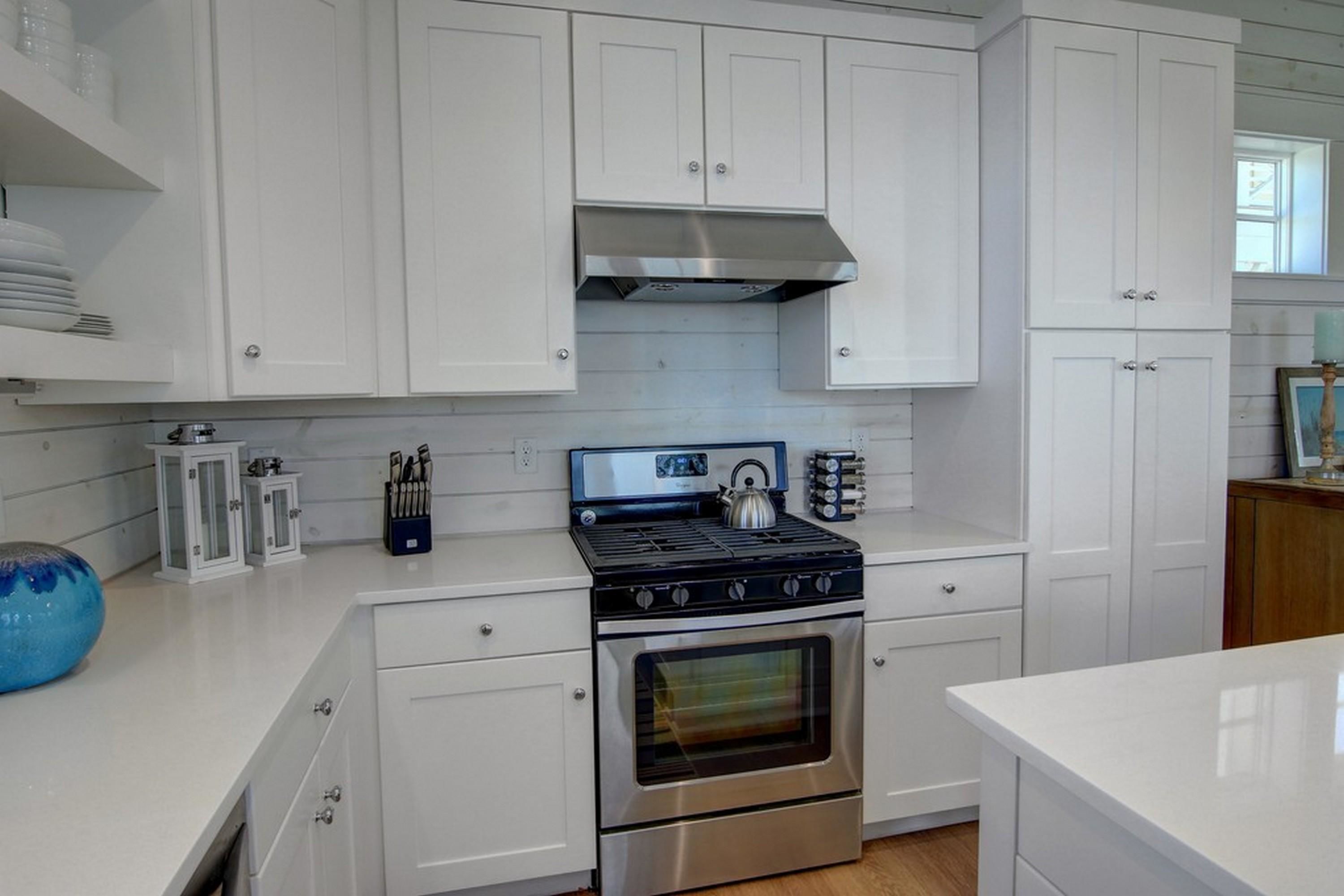A modern kitchen with white cabinetry, a stainless steel stove, and an oven.