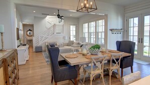 A spacious living area with a wooden dining table, comfortable seating, and a staircase leading to an upper level. - Cinnamon Shore- Sea Change 115 FI (Port Aransas)