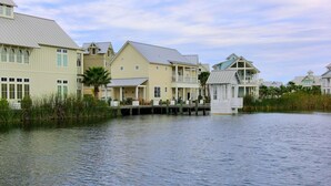 A waterfront property with multiple buildings, including a large house with a balcony and a smaller structure with a porch. - Cinnamon Shore- Sea Change 115 FI (Port Aransas)