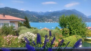 A garden with lavender and other flowers, a view of a lake, and mountains in the background.