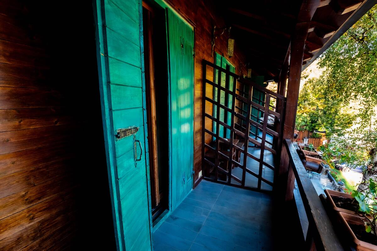 A wooden staircase leading to a covered outdoor area with a view of a garden.