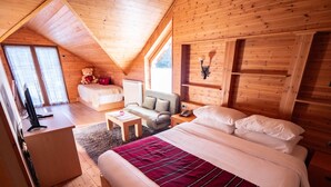 A cozy wooden cabin bedroom with a large bed, a desk, a chair, and a TV. - Natyral Razma Resort (Shkrel)