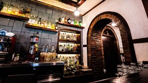 A bar area with shelves of liquor bottles, a coffee machine, and a brick archway. - Natyral Razma Resort (Shkrel)