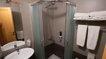 A modern bathroom with a glass-enclosed shower, a sink, and a towel rack with multiple towels.
