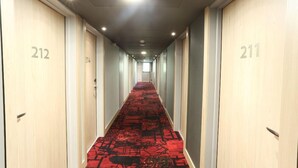 A hotel hallway with doors numbered 212 and 211, featuring a red carpet and overhead lighting. - Arena Hotel La Defense (Nanterre)