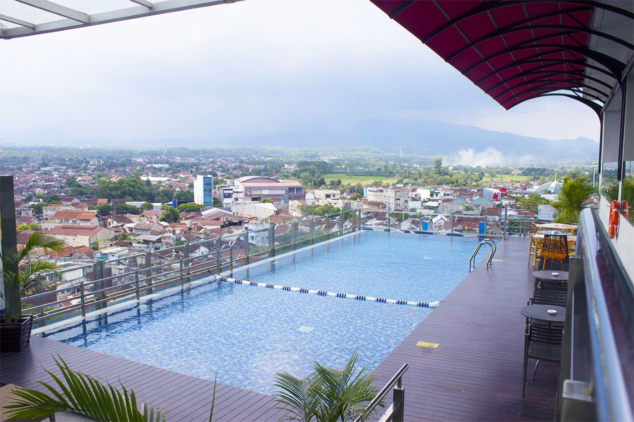 Una piscina en la azotea con vistas a un paisaje urbano y montañas a lo lejos.