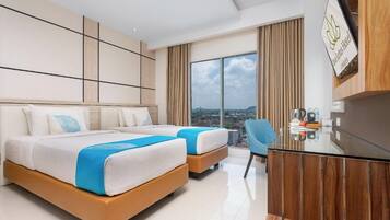 A modern hotel room with two beds, a desk, and a view of the city.