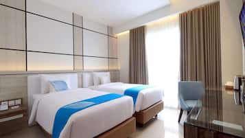 A hotel room with two beds, a desk, and a TV.