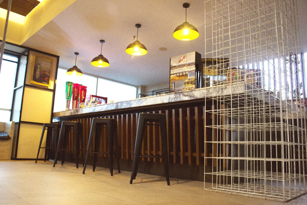 A bar area with three stools, a counter, and hanging pendant lights.