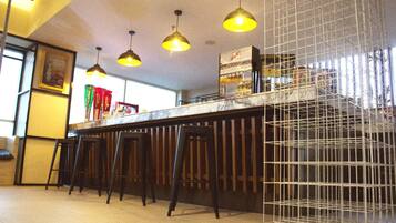 A bar area with three stools, a counter, and hanging pendant lights.