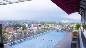 Una piscina en la azotea con vistas a un paisaje urbano y montañas a lo lejos.