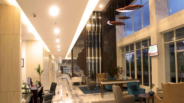 Un moderno vestíbulo de hotel con mostrador de recepción, zona de estar y amplias ventanas.