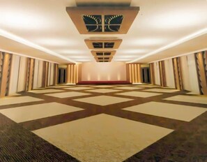 Un amplio pasillo de hotel con alfombra estampada, iluminación empotrada y un diseño simétrico.