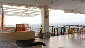 Un balcón amplio con vistas a la ciudad, amueblado con sillas anaranjadas y una mesa de madera.