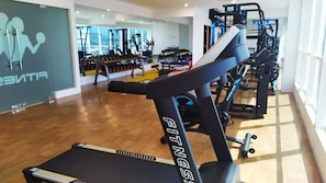 Un gimnasio con equipo de ejercicio, un espejo grande y suelo de madera.