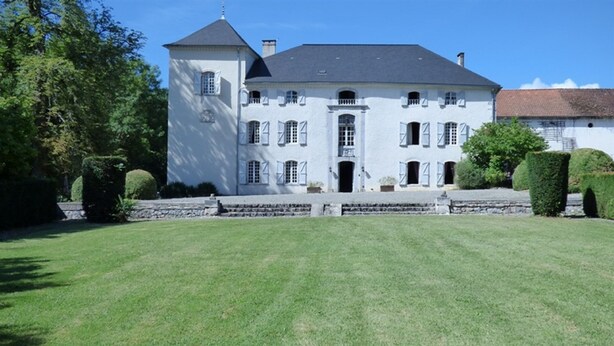 Un grand bâtiment blanc à la façade sym étrique, doté de nombreuses fenêtres et d’une entrée centrale.