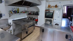 Une cuisine professionnelle équipée d’appareils en acier inoxydable, d’une grande cuisinière et d’une hotte aspirante.