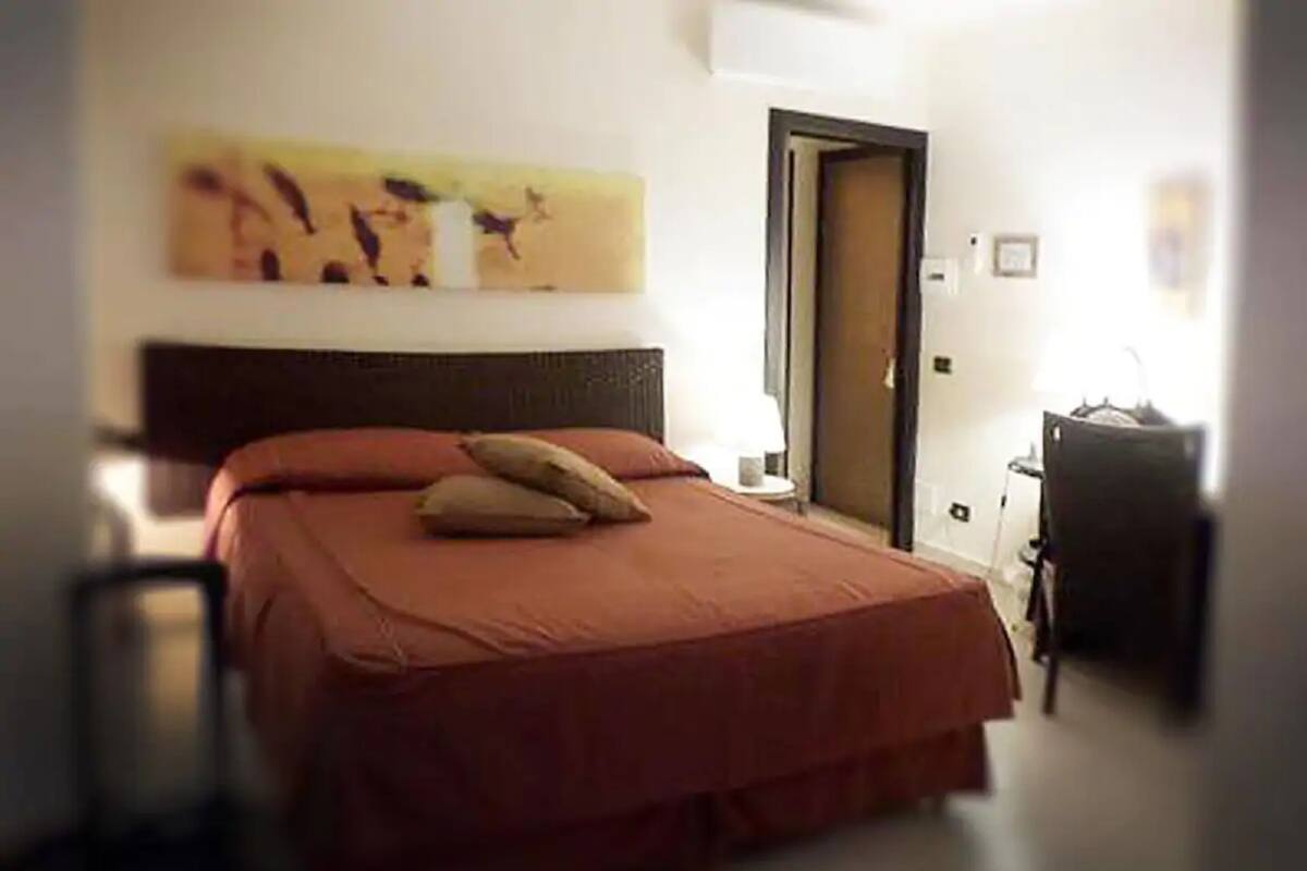 A bedroom with a bed, a door, and a wall with artwork.