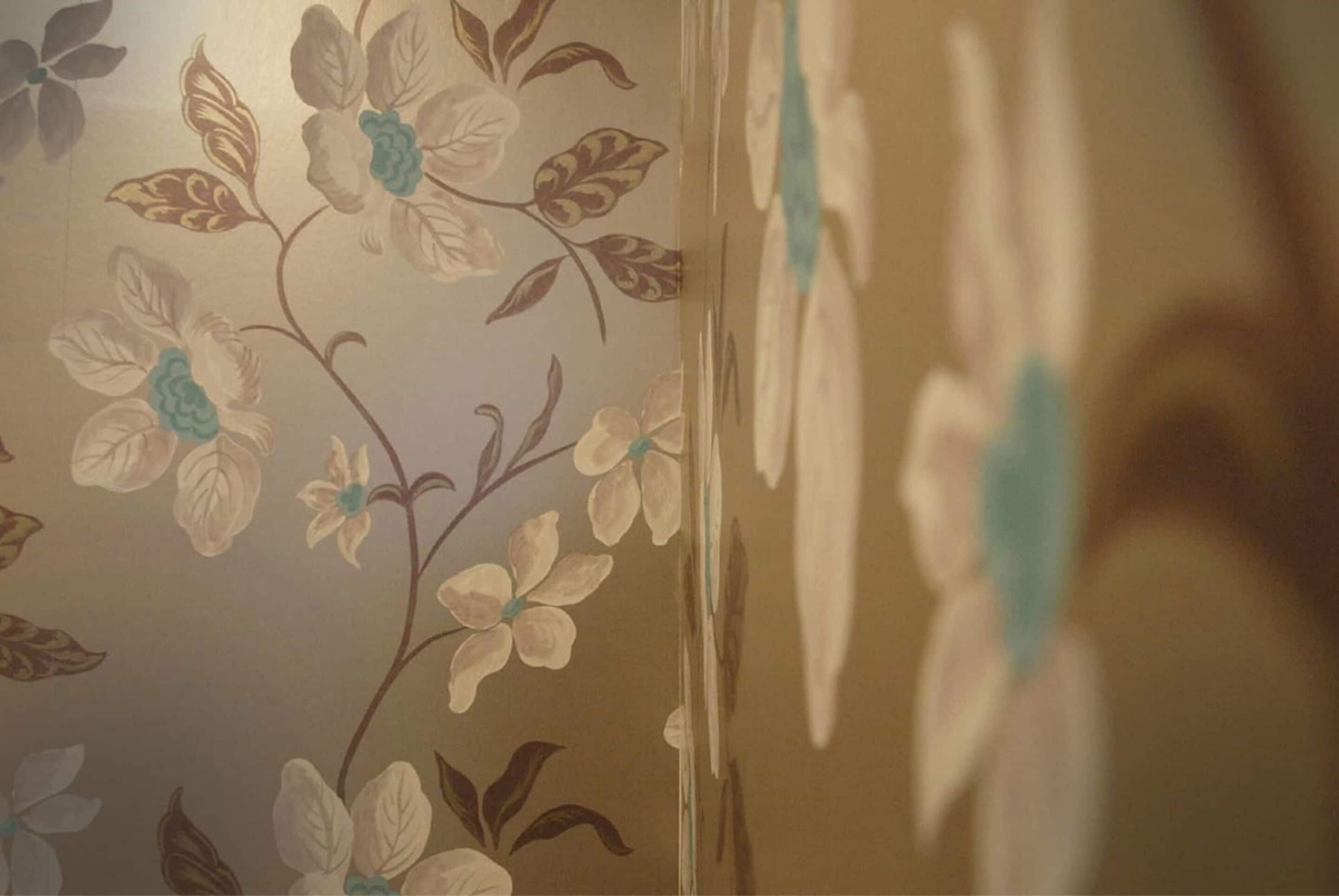 Eine Wand mit einem floralen Wandpapier-Muster.