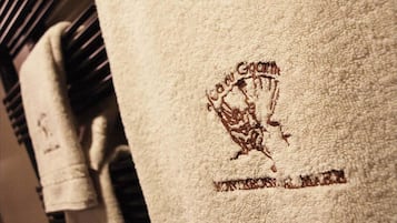 Una toalla con bordado de texto y logotipo, colgada en un perchero.