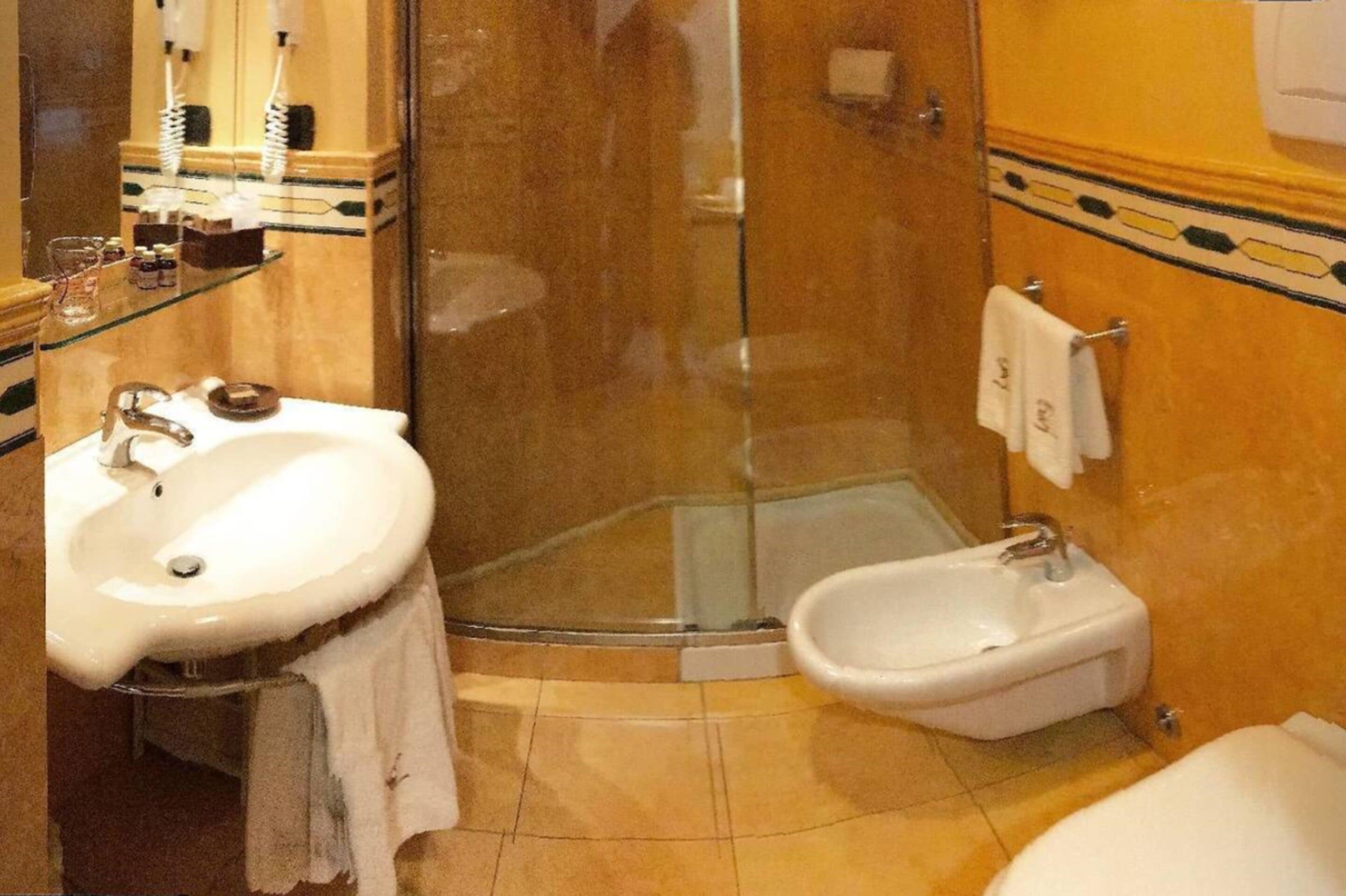 A bathroom with a white sink, a bidet, and a glass-enclosed shower.