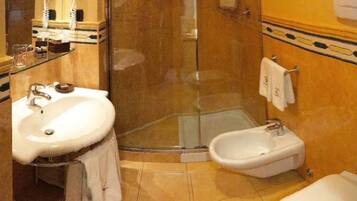 A bathroom with a white sink, a bidet, and a glass-enclosed shower.