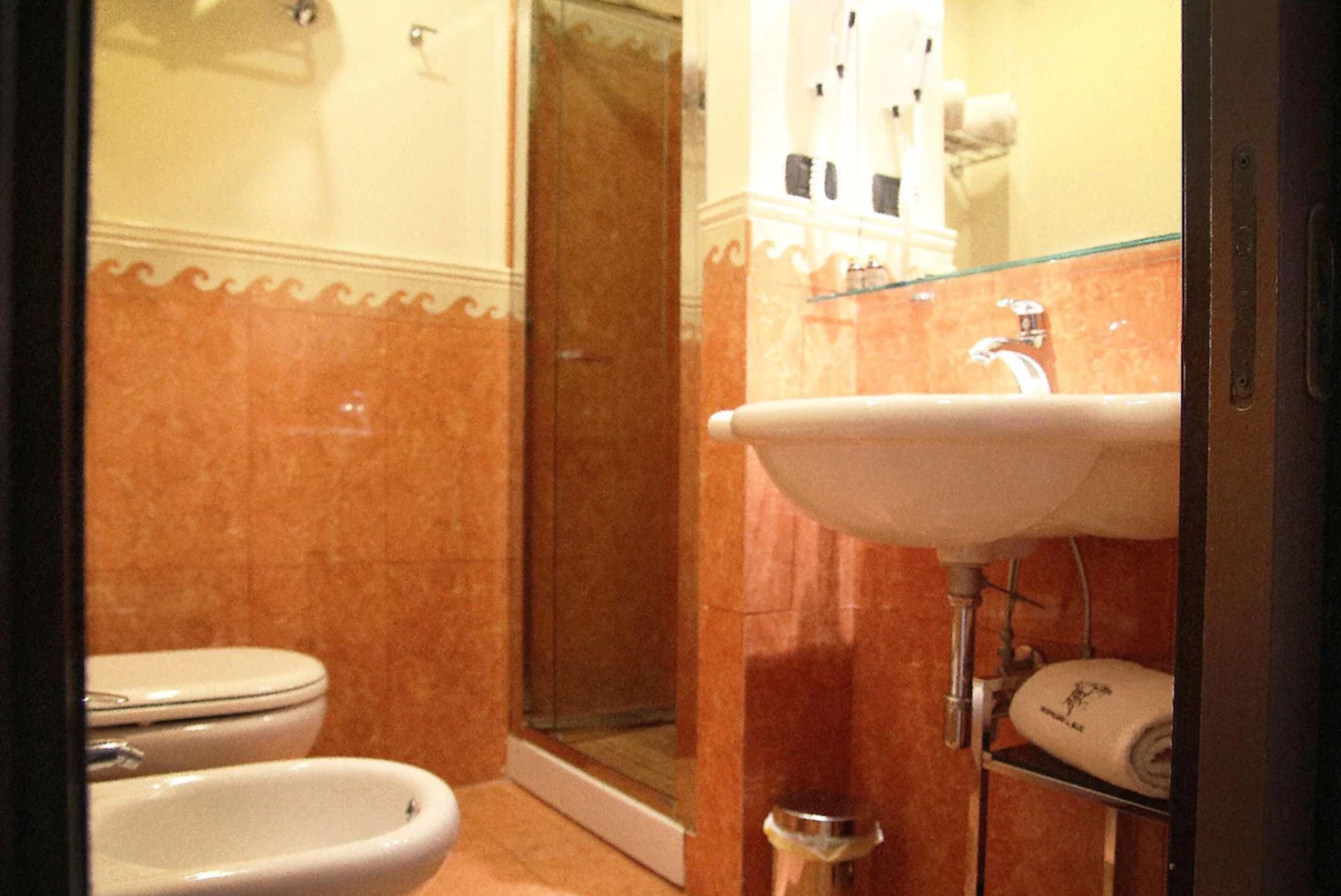 A bathroom with a toilet, bidet, and glass shower enclosure.