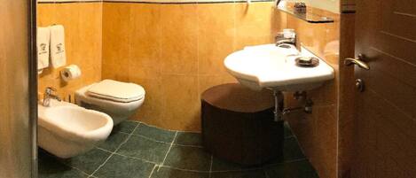 A small bathroom with a toilet, bidet, and sink.