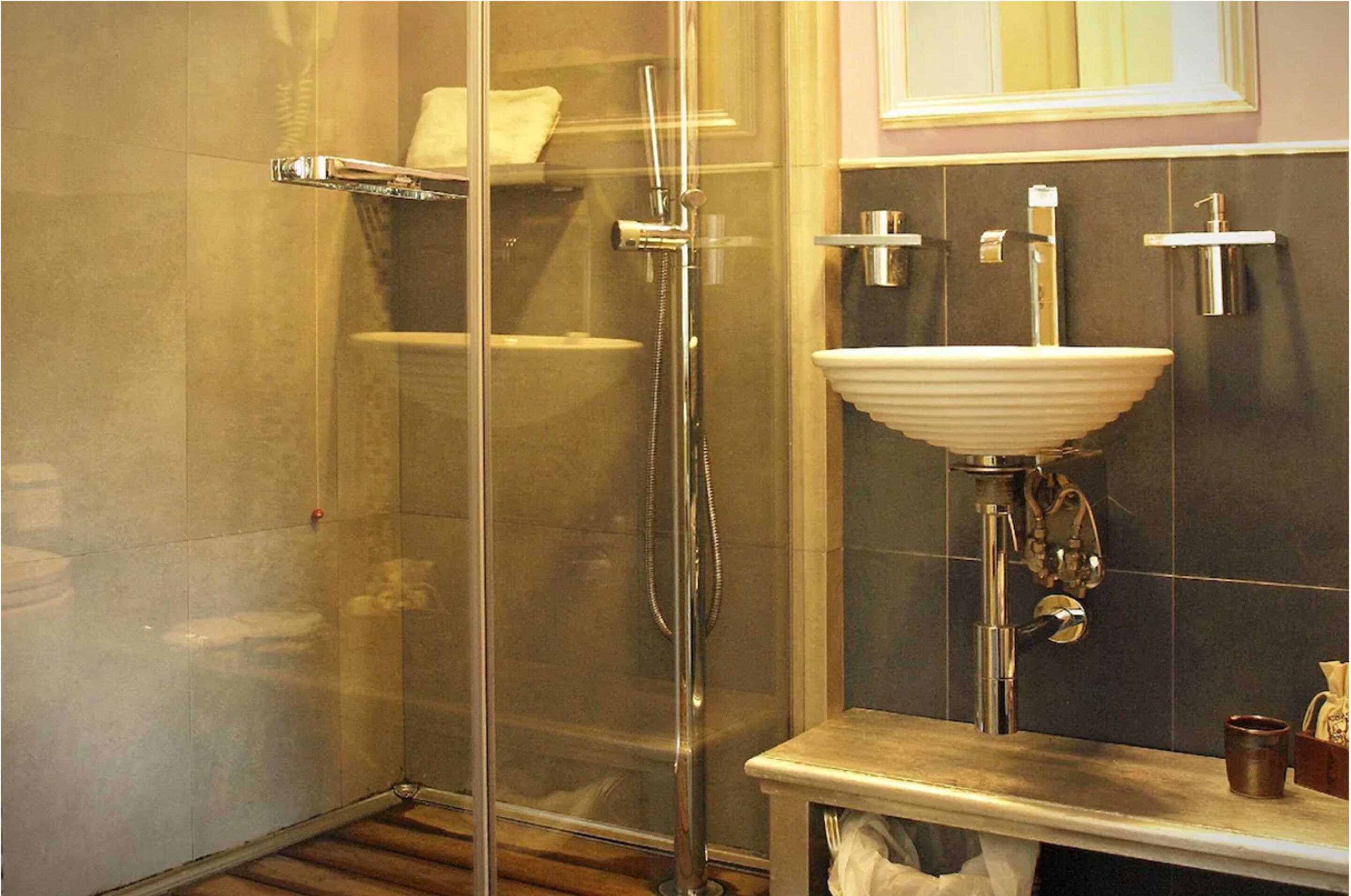 Une salle de bain avec une douche à parois de verre, un lavabo blanc et un miroir au-dessus du lavabo.