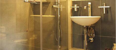 Un baño con cabina de ducha de vidrio, un lavabo blanco y un espejo sobre el lavabo.
